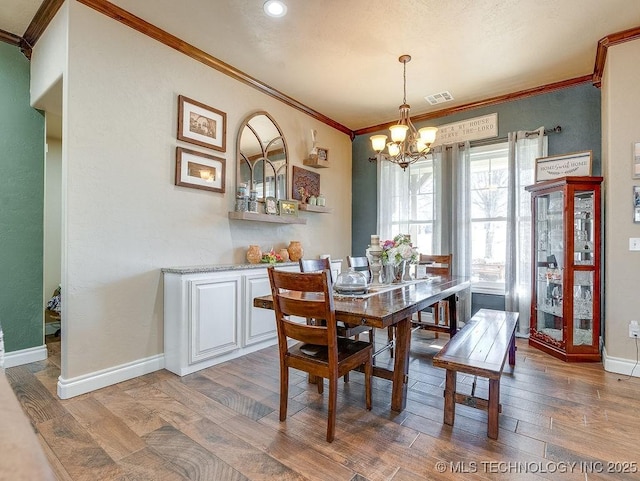 dining space with crown molding, hardwood / wood-style floors, and a notable chandelier