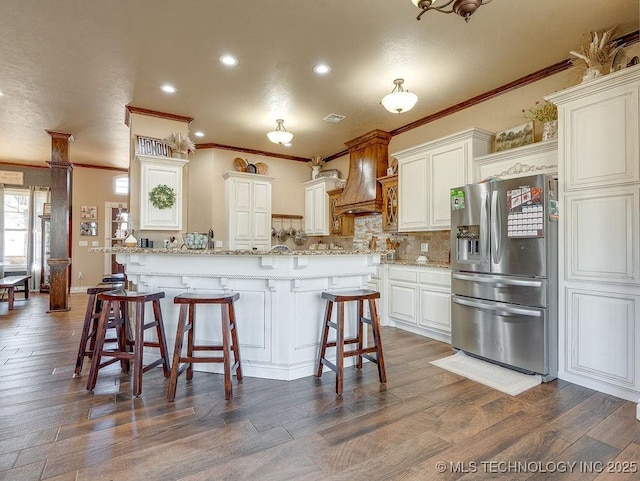 kitchen featuring white cabinets, stainless steel fridge, a kitchen breakfast bar, dark wood-type flooring, and custom range hood