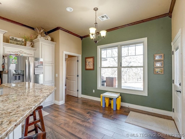 kitchen featuring white cabinetry, hanging light fixtures, light stone counters, ornamental molding, and stainless steel fridge with ice dispenser