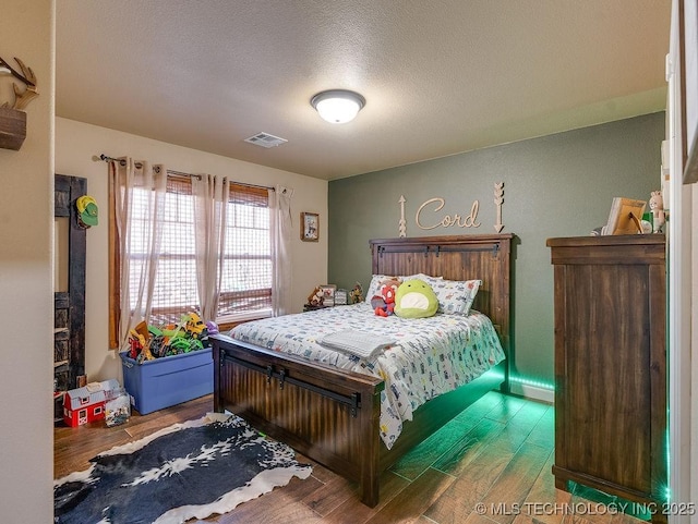 bedroom featuring wood-type flooring and a textured ceiling