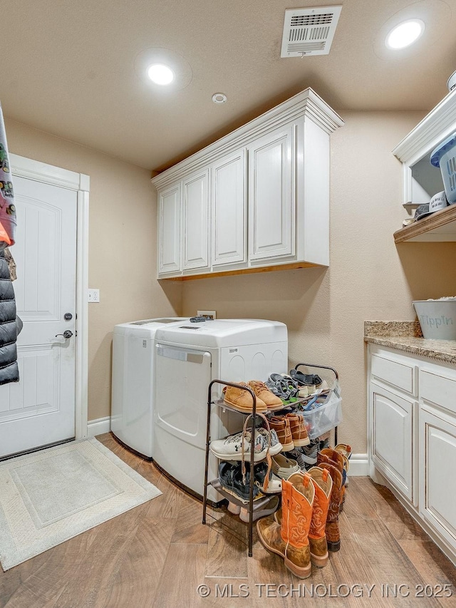 clothes washing area featuring separate washer and dryer, cabinets, and light parquet flooring