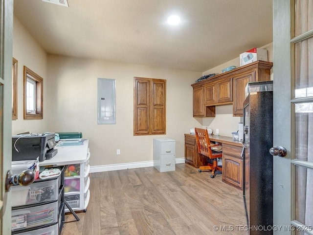 office featuring built in desk, electric panel, and light wood-type flooring