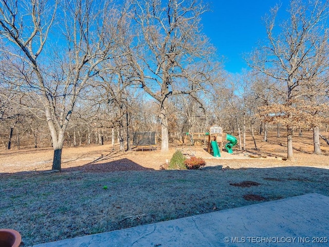 view of yard with a playground and a trampoline