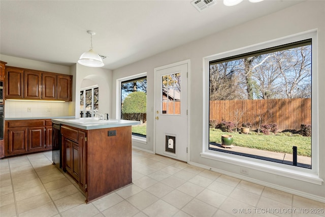 kitchen featuring decorative light fixtures, dishwasher, sink, backsplash, and a center island