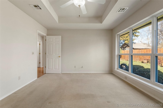 carpeted empty room featuring ceiling fan and a tray ceiling