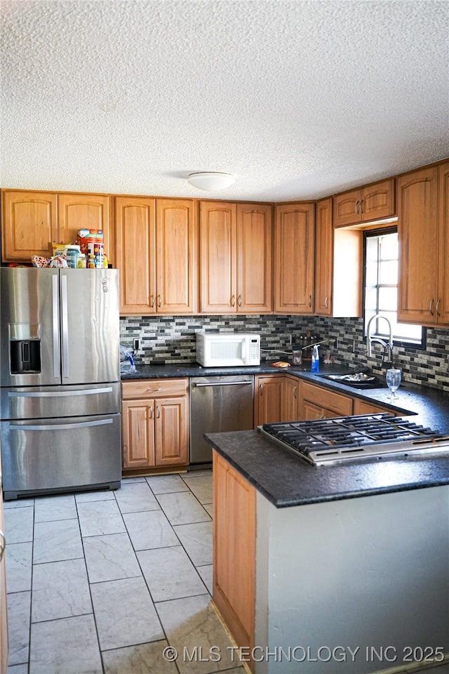 kitchen with appliances with stainless steel finishes, sink, backsplash, and a textured ceiling