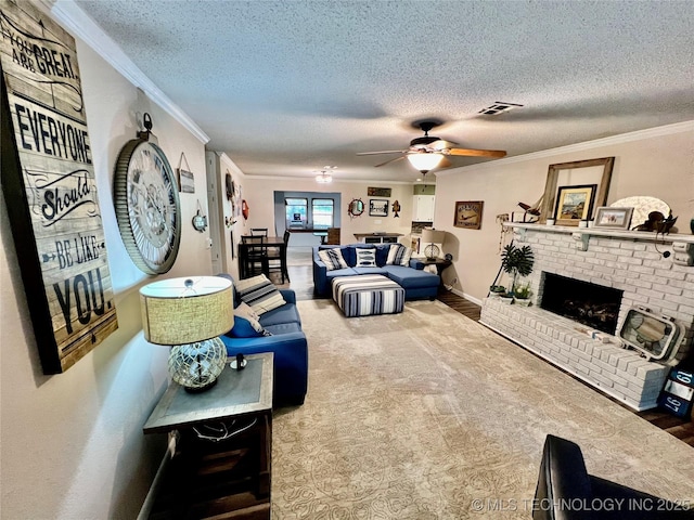 living room featuring a fireplace, ornamental molding, and a textured ceiling