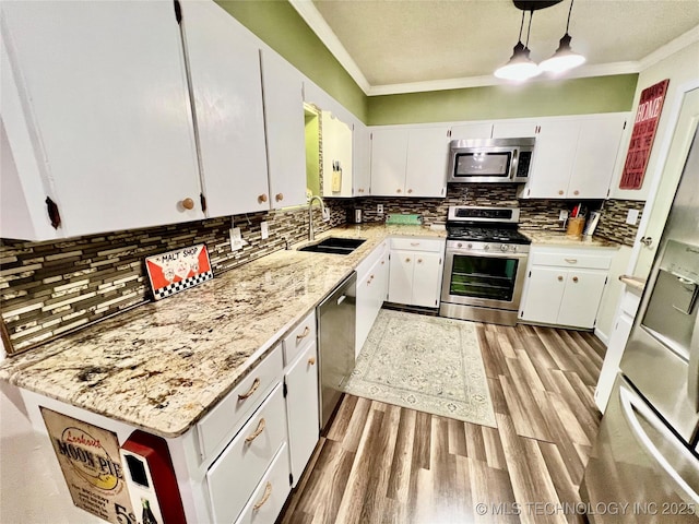 kitchen featuring appliances with stainless steel finishes, decorative light fixtures, white cabinetry, sink, and light stone counters