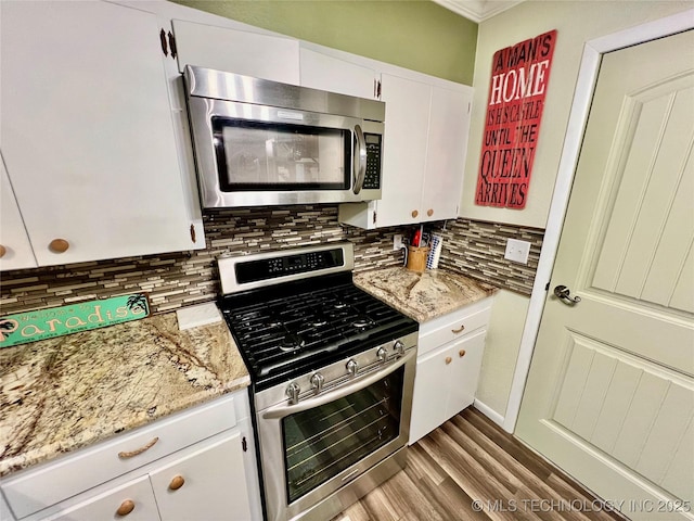 kitchen with white cabinetry, light stone countertops, decorative backsplash, and stainless steel appliances