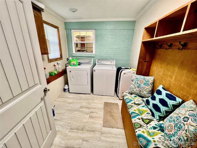 laundry area featuring crown molding, washing machine and dryer, and light tile patterned flooring