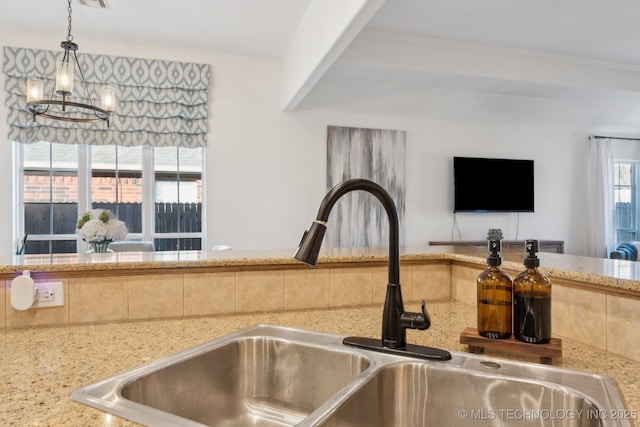 details featuring sink, pendant lighting, a notable chandelier, and light stone counters