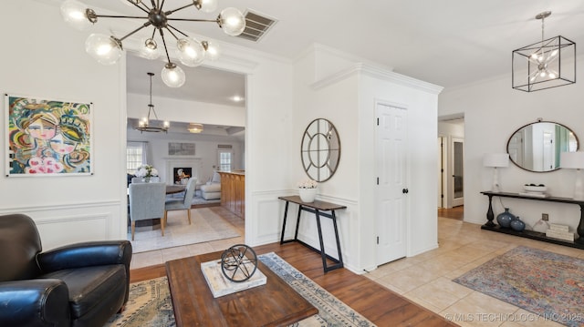 living room featuring light tile patterned flooring, ornamental molding, and an inviting chandelier