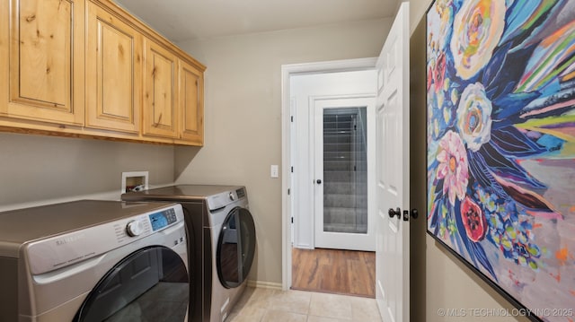 laundry area with cabinets, washing machine and dryer, and light tile patterned floors