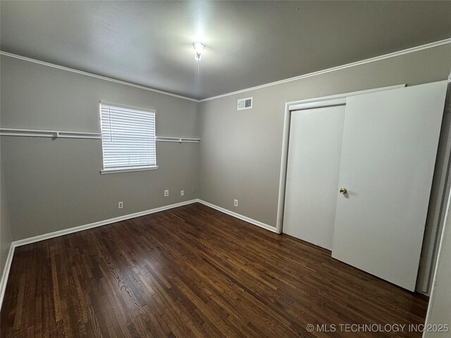 unfurnished bedroom with ornamental molding, dark hardwood / wood-style flooring, and a closet