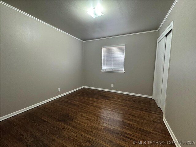 unfurnished bedroom featuring crown molding, dark hardwood / wood-style floors, and a closet