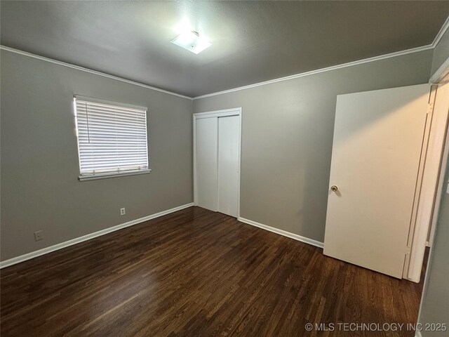 unfurnished bedroom with crown molding, dark wood-type flooring, and a closet