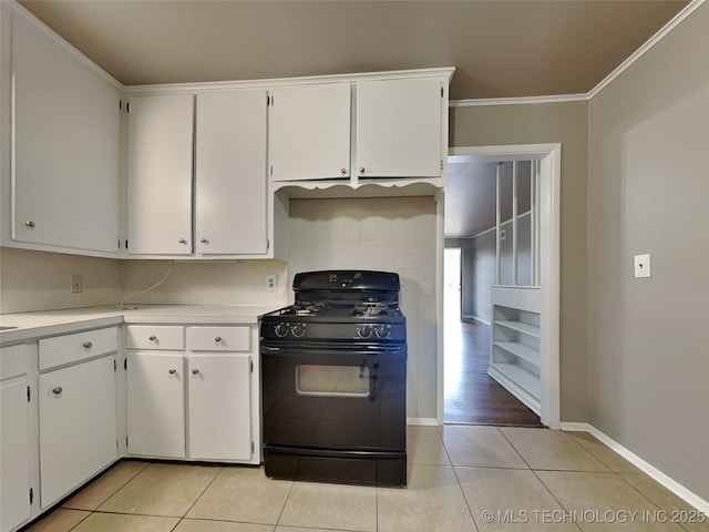 kitchen with white cabinetry, light tile patterned floors, ornamental molding, and gas stove