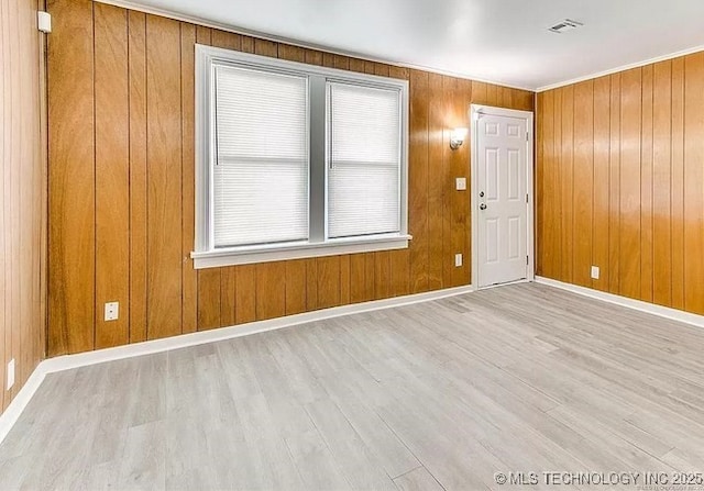 unfurnished room featuring crown molding, light hardwood / wood-style floors, and a wealth of natural light