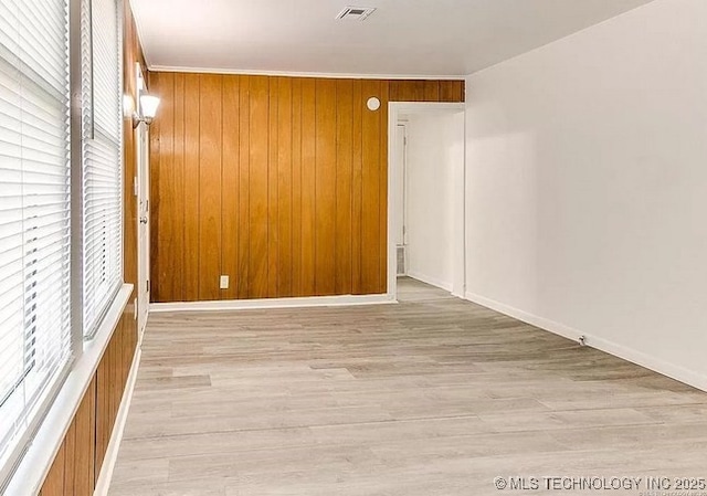 empty room with wooden walls and light hardwood / wood-style flooring