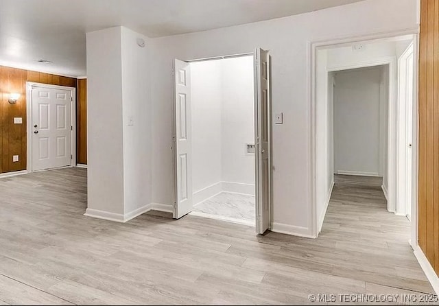 hallway featuring light hardwood / wood-style floors and wood walls