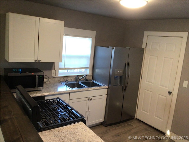 kitchen featuring appliances with stainless steel finishes, sink, white cabinets, and dark hardwood / wood-style floors