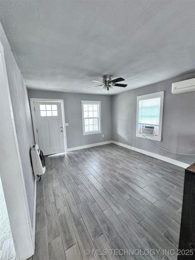 foyer entrance featuring heating unit, a textured ceiling, a wall unit AC, cooling unit, and ceiling fan