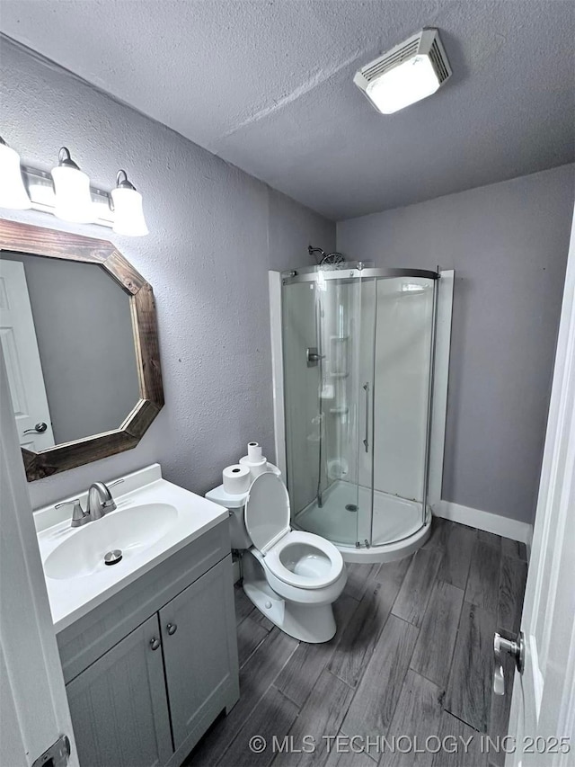 bathroom with hardwood / wood-style flooring, vanity, walk in shower, toilet, and a textured ceiling