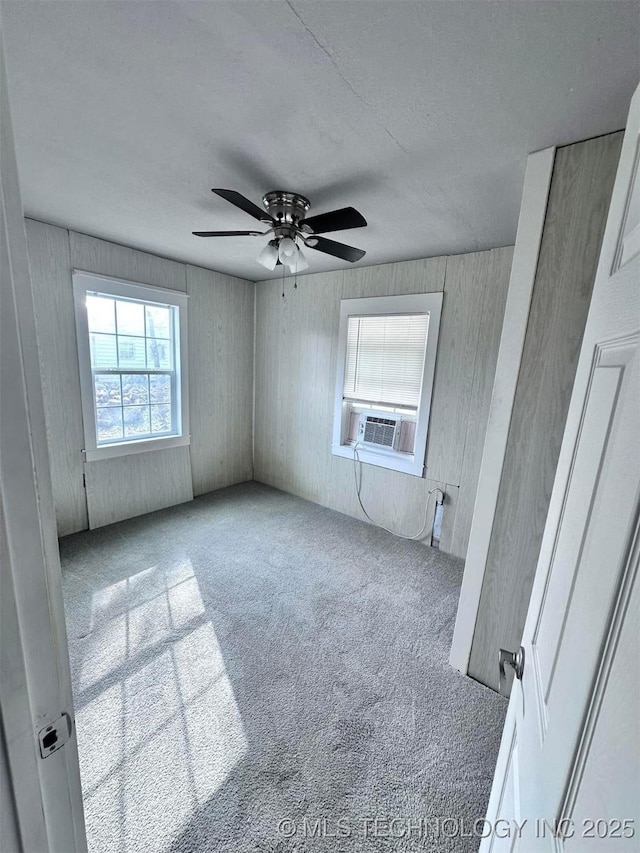 carpeted empty room featuring cooling unit and ceiling fan