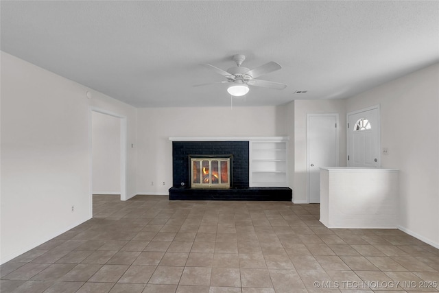 unfurnished living room featuring ceiling fan, a textured ceiling, a brick fireplace, and light tile patterned floors