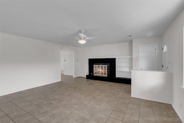 unfurnished living room featuring light tile patterned flooring, a brick fireplace, and ceiling fan