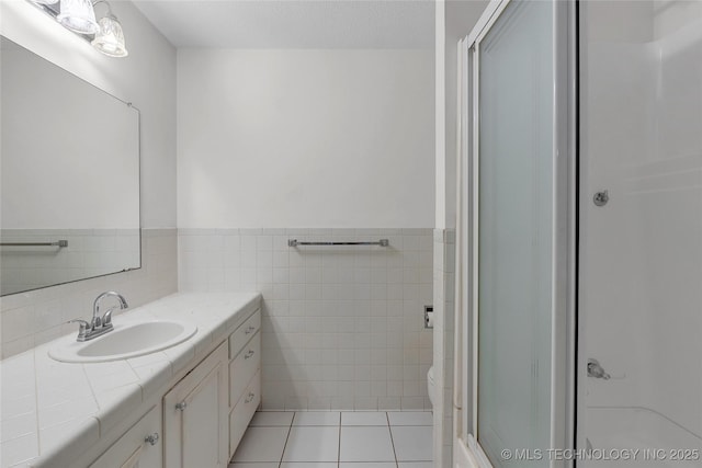 bathroom featuring tile walls, tile patterned flooring, vanity, a textured ceiling, and a shower with shower door