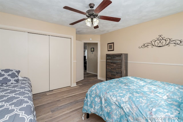 bedroom with hardwood / wood-style floors, a textured ceiling, ceiling fan, and a closet