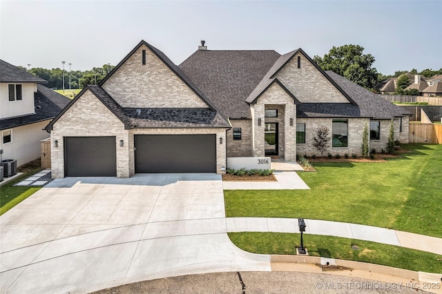 french provincial home with a garage, central AC unit, and a front lawn