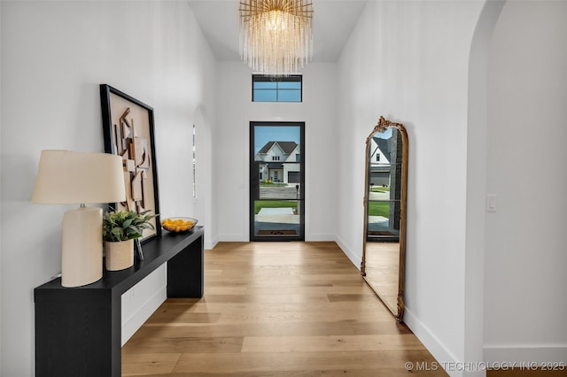 entrance foyer with a towering ceiling, a chandelier, and light wood-type flooring