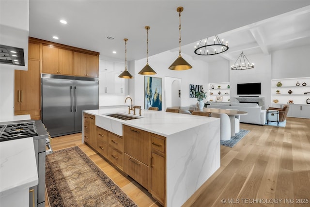 kitchen with a large island, sink, appliances with stainless steel finishes, beam ceiling, and decorative light fixtures