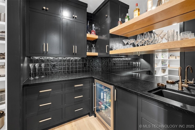 kitchen featuring sink, light hardwood / wood-style flooring, wine cooler, tasteful backsplash, and dark stone counters