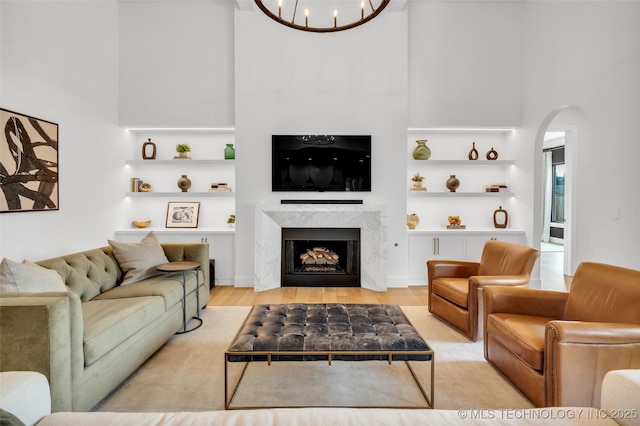 living room with light hardwood / wood-style floors, a premium fireplace, and a chandelier