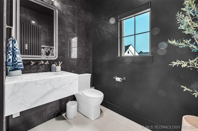 bathroom featuring tile walls and toilet