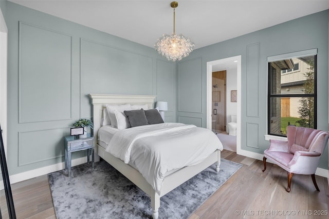 bedroom featuring a notable chandelier, ensuite bath, and wood-type flooring