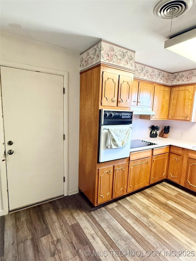 kitchen with black electric stovetop, light hardwood / wood-style floors, and white oven