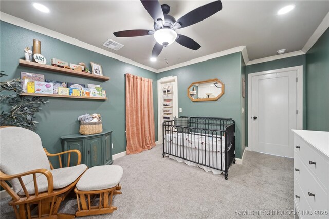 bedroom featuring crown molding, light colored carpet, a nursery area, and ceiling fan