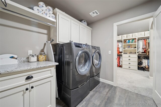 laundry area with cabinets, washing machine and dryer, and hardwood / wood-style floors