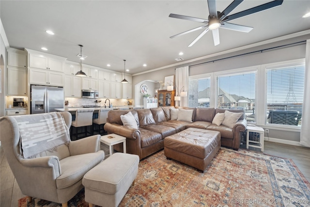 living room with ornamental molding, ceiling fan, and light wood-type flooring