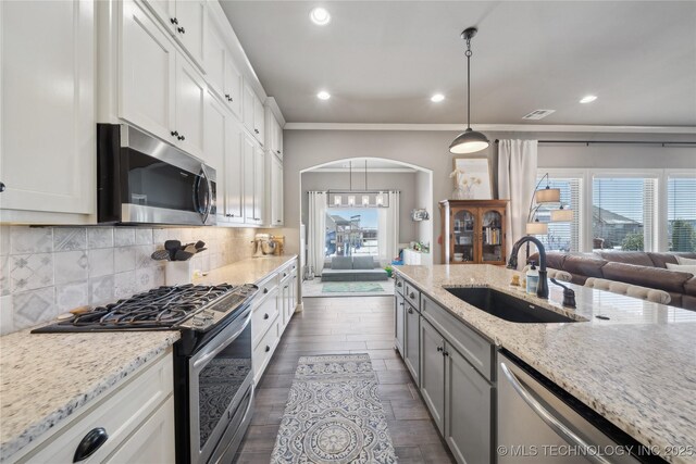 kitchen featuring sink, appliances with stainless steel finishes, white cabinetry, light stone countertops, and decorative light fixtures