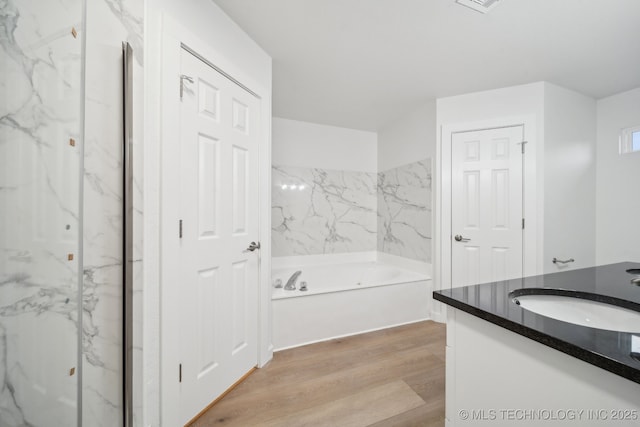 bathroom with wood-type flooring, vanity, and a tub