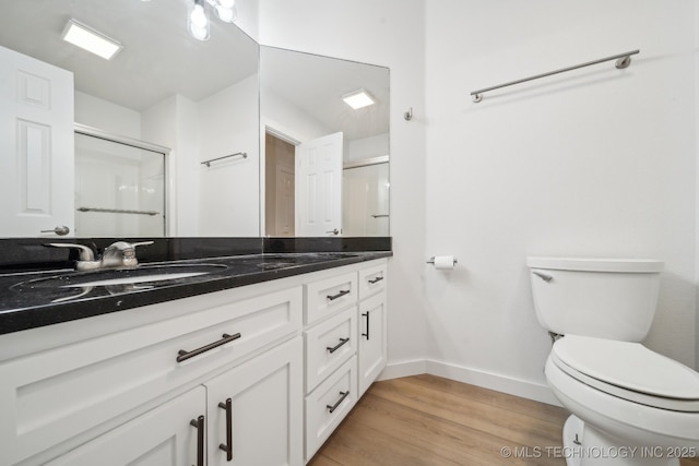 bathroom with hardwood / wood-style flooring, vanity, toilet, and walk in shower