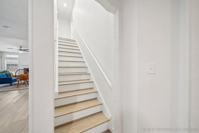 stairway with wood-type flooring and ceiling fan