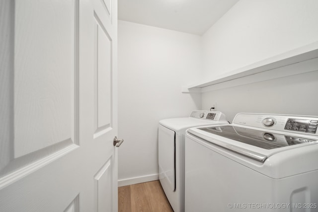 washroom with washer and clothes dryer and light wood-type flooring