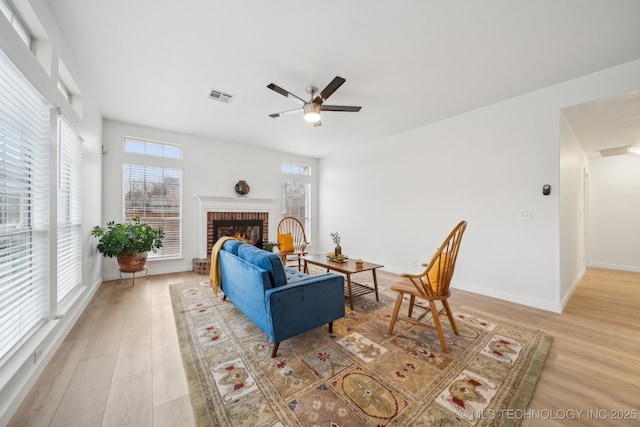 living room with ceiling fan, a fireplace, and light hardwood / wood-style flooring