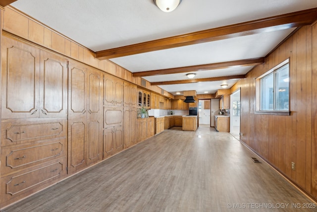 interior space featuring light wood-style floors, visible vents, beamed ceiling, and wooden walls